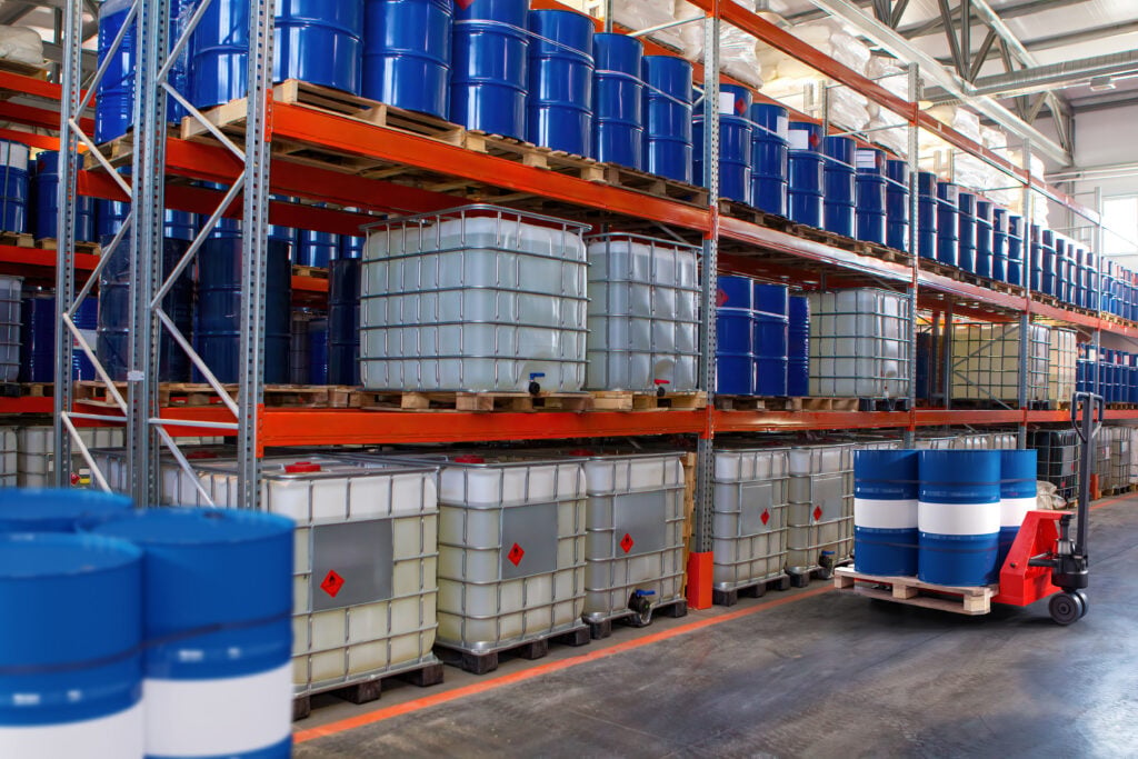 Chemical warehouse. Barrels with flammability symbol. Forklift in warehouse area. Oil barrels are stored on racks. Warehouse
