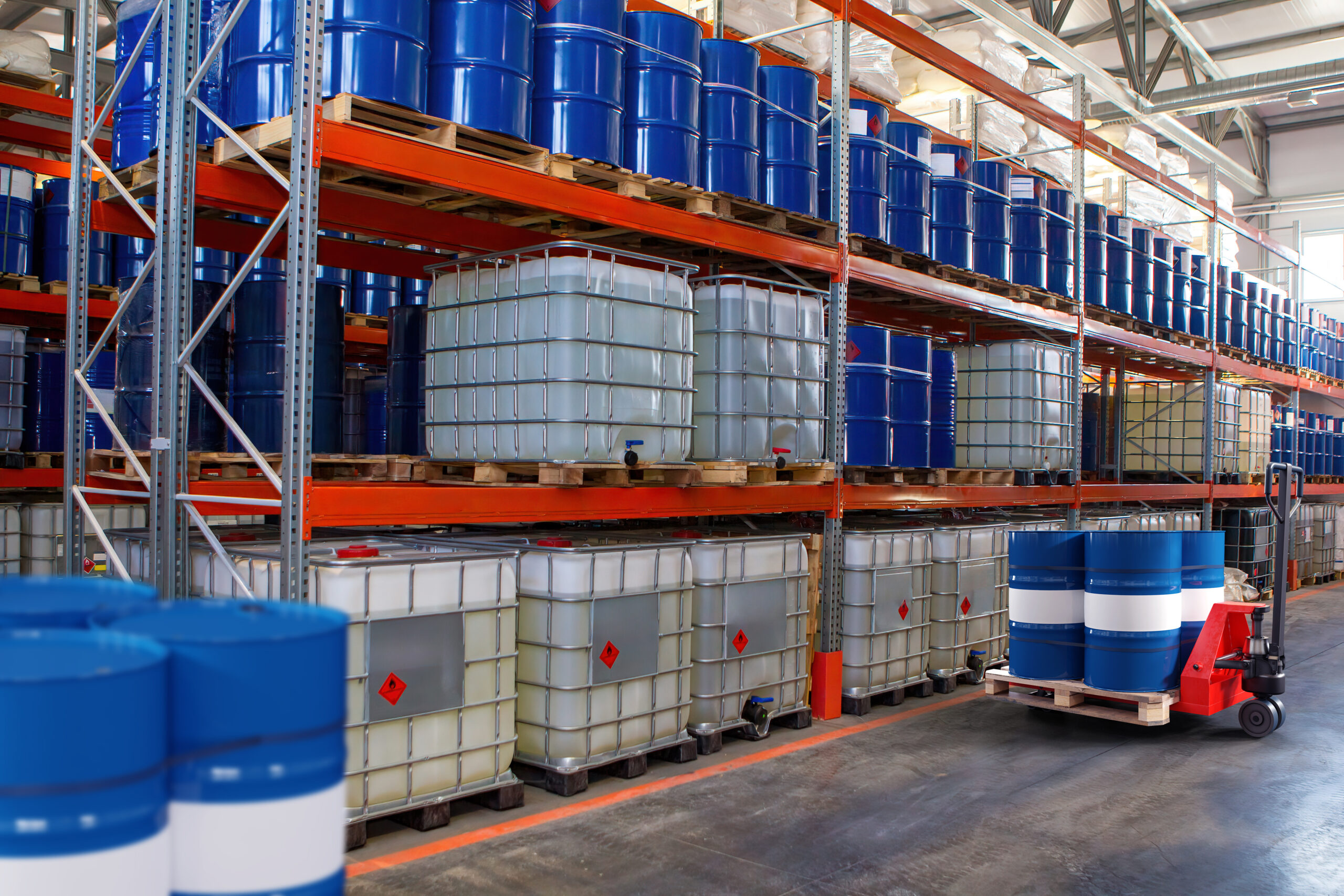 Chemical warehouse. Barrels with flammability symbol. Forklift in warehouse area. Oil barrels are stored on racks. Warehouse