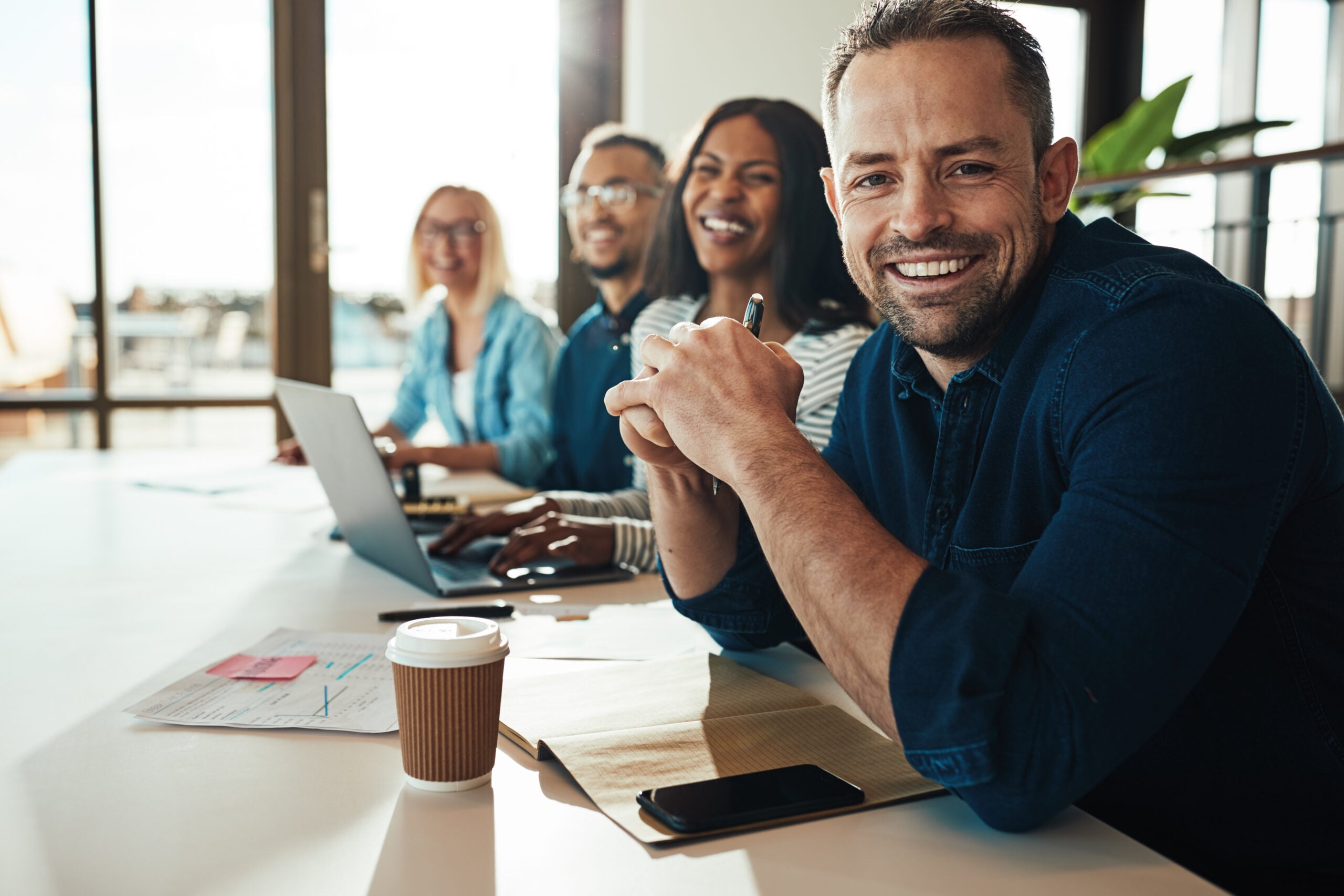 Smiling mature businessman sitting with colleagues in an office